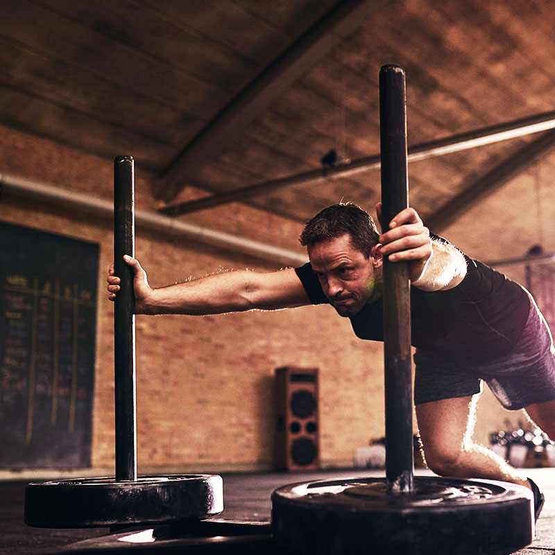 Athlete doing a sled push strength and conditioning exercise for sports training.